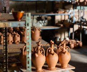 Clay jugs and utensils on racks in store
