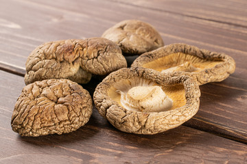 Group of five whole dry mushroom shiitake on brown wood