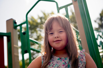 A portrait of trisomie 21 child girl outside having fun on a park