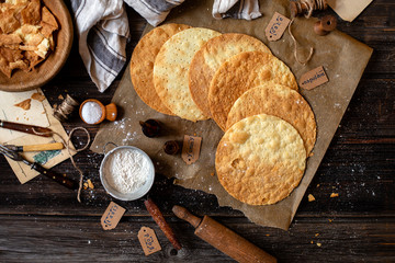 overhead shot of tasty crispy baked round puff pastry layers of homemade traditional Russian napoleon cake on parchment on rustic wooden table