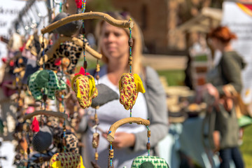 A woman is standing at a booth at a street festival and looking for baby mobiles. Concept: toys or festivals