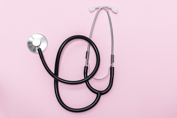 Medical stethoscope on light pink background. Cardiology and health care concept. World heart day concept.