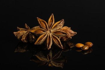 Group of three whole three pieces of dry brown star anise illicium verum isolated on black glass