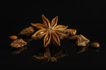 One whole lot of pieces of dry brown star anise illicium verum isolated on black glass