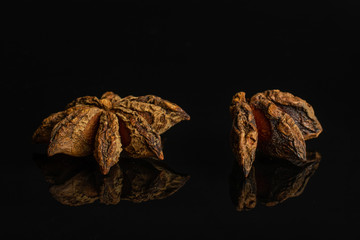 Group of one whole one quarter of dry brown star anise illicium verum isolated on black glass