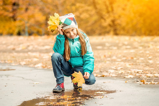 pretty little girl squatting with leaves in hand