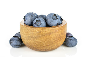 Lot of whole fresh blue bilberry in tiny wooden bowl isolated on white background