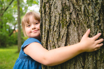 A portrait of trisomie 21 child girl outside having fun on a park