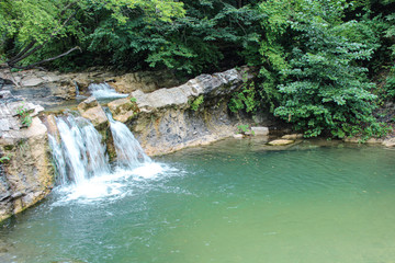 Naklejka premium Mountain waterfall. Stone coast. Waterfall in the forest.