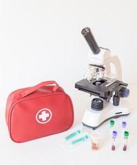 Laboratory equipment and first aid kit. Microscope, test tubes with blood.