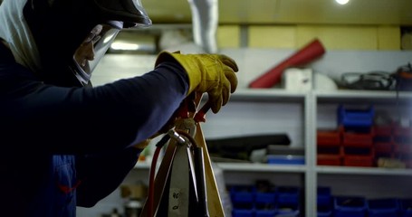 Welding master-a man in gloves and a helmet working with a part that cooks, collects it.