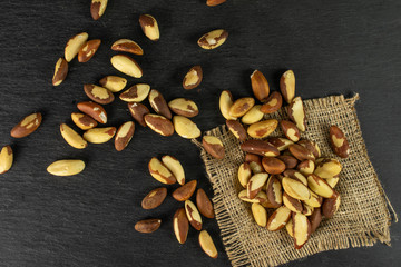 Lot of whole raw brown brazil nut on natural sackcloth flatlay on grey stone