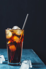 Cold brew coffee in a glass with metal straw on a dark background.