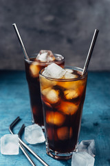Cold brew coffee in a glass with metal straw on a dark background.