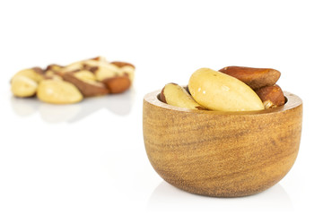 Lot of whole raw brown brazil nut in tiny wooden bowl isolated on white background