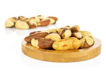 Lot of whole raw brown brazil nut on bamboo coaster isolated on white background