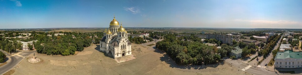Fototapeta na wymiar The Golden-domed Ascension Cathedral on Yermak Square in the provincial town of Novocherkassk in southern Russia. Luxurious aerial view on a sunny summer day mid-August.
