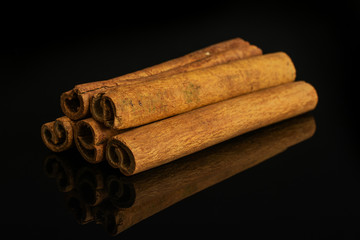 Group of five whole dry brown cinnamon isolated on black glass