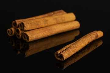 Group of six whole dry brown cinnamon isolated on black glass