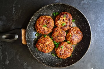 Meat cutlets. Cutlets in a pan on a black concrete table background. Delicious tasty food. Cutlets in the black plate isolated.