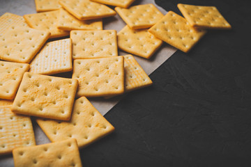 Salty square crackers on a paper and dark concrete background
