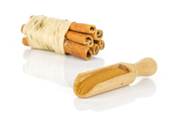 Group of six whole dry brown cinnamon wrapped in natural bast in a wooden scoop isolated on white background