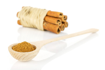 Group of six whole dry brown cinnamon wrapped in natural bast in a wooden spoon isolated on white...