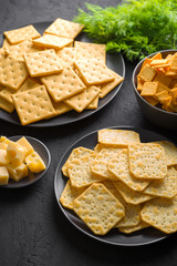 Crackers with cheese and greens on a dark background.