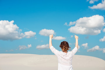 Confident young woman raising her fist up in the sky. Feeling motivated.