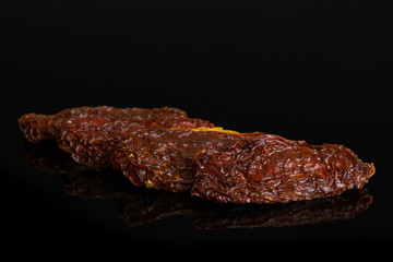 Group of four whole dried red tomato isolated on black glass