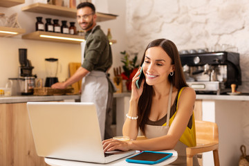Wife receiving calls from clients while sitting at the laptop