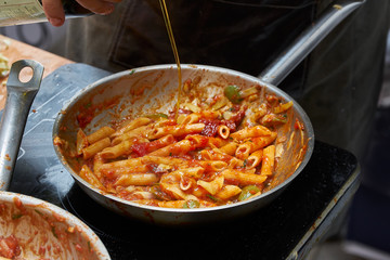 Fresh pasta with sausages, olives and basil leaves.