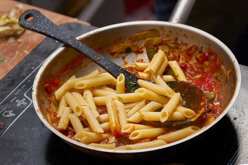 cooking food of italian cuisine, pasta with tomato sauce, detailed view of spoon and pan frying
