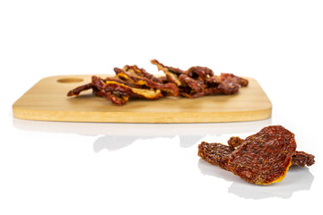 Lot of whole dried red tomato on bamboo cutting board isolated on white background