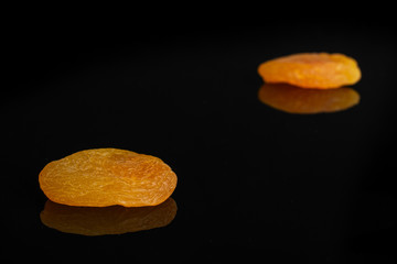 Group of two whole dried orange apricot isolated on black glass