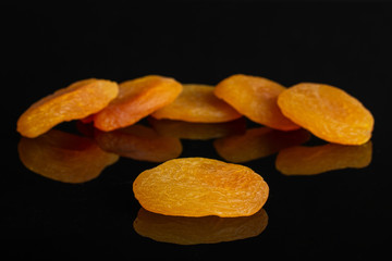 Group of six whole dried orange apricot isolated on black glass