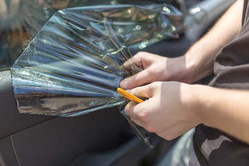 Close up of worker pulling off sun protection tinted foil from side car window.