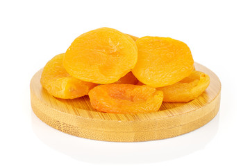 Lot of whole dried orange apricot on round bamboo coaster isolated on white background