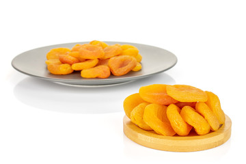 Lot of whole dried orange apricot on round bamboo coaster on gray ceramic plate isolated on white background