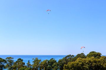two paragliders flying over the sea, beautiful view and blue sky.