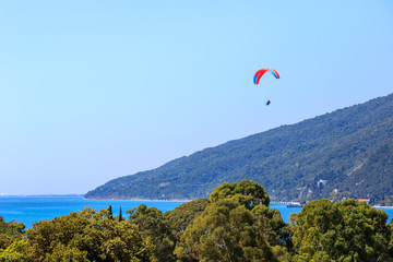 paragliding with an instructor over the sea near the mountain.
