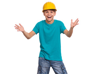 Portrait of smiling teen boy wearing yellow hard hat, isolated on white background. Beautiful student caucasian young teenager in helmet looking at camera. Cheerful child with raised hands shouting.