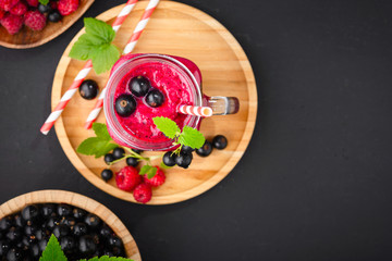 Raspberry and currant berry smoothie in a glass bottle with a straw and mint leaf