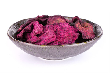 Obraz premium Lot of slices of dried red beetroot in dark ceramic bowl isolated on white background