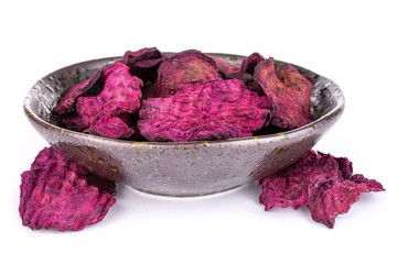 Obraz premium Lot of slices of dried red beetroot in dark ceramic bowl isolated on white background