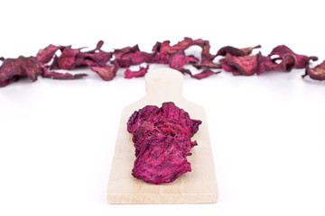 Obraz premium Lot of slices of dried red beetroot on small wooden cutting board isolated on white background