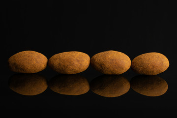 Group of four whole sweet brown chocolate cinnamon almond isolated on black glass