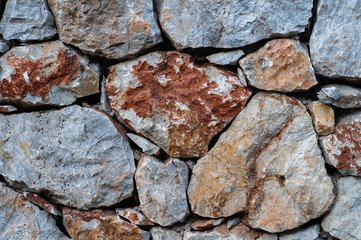 Modern wall of large unprocessed pieces of rock, stones. Background stone wall.