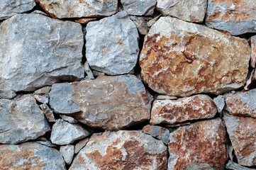 Modern wall of large unprocessed pieces of rock, stones. Background stone wall.