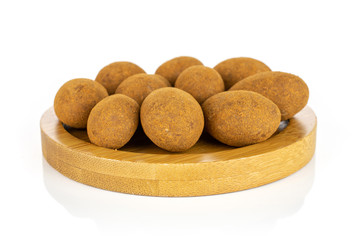 Lot of whole sweet brown chocolate cinnamon almond on round bamboo coaster isolated on white background